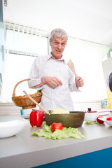 Elderly man preparing vegetable launch in the kitchen