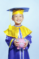 Happy scholar dressed toddler with piggybank