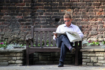 Hombre leyendo el periódico en un banco en la ciudad de Londres