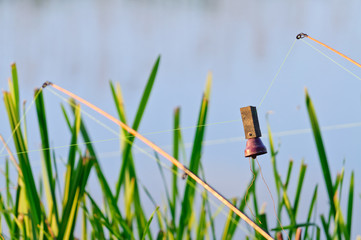 Fishing rod with a bell on the background of sky and water