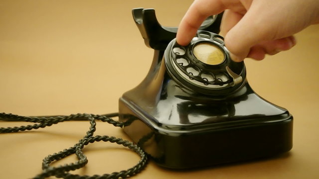 male hand on very old telephone on brown background