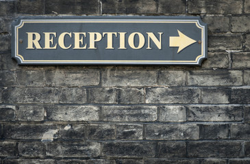 Receptions arrow sign on brick wall
