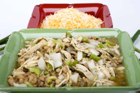 White chicken chili in ceramic dish with cheese & ingredients