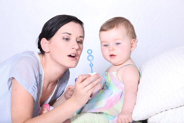 a baby and her mother looking a soap bubble solution