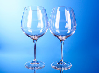 Two empty wine glasses on blue background