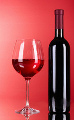 Wine bottle and glass on red background