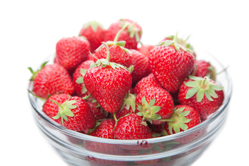 Fresh strawberries in a glass dish on white.