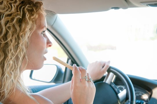 Young woman eating sweets while driving car