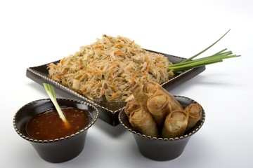Pancit on a ceramic dish with egg rolls and sweet and sour sauce