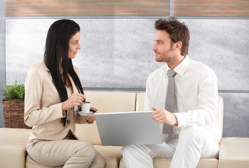 Elegant businesspeople using laptop talking