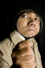Detective looking for clues through magnifying glass