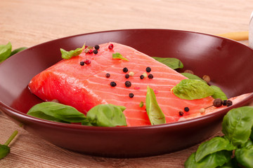 Red fish on the plate with pepper and green leaves