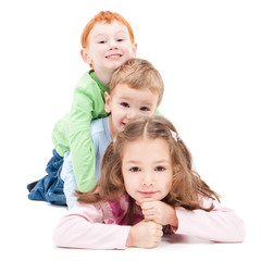 Three smiling kids lying on top of each other