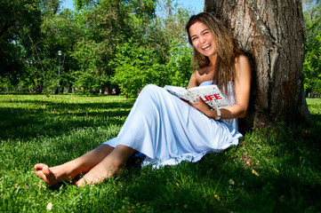 young woman reading book in park