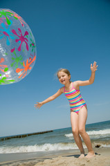 Little girl playing ball on the beach