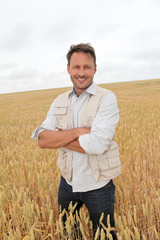Naklejka na ściany i meble Portrait of handsome man standing in wheat field
