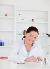 Obraz na płótnie Canvas Portrait of a cute scientist preparing a report looking at the c