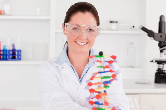 Smiling scientist showing the dna double helix model - Powered by Adobe
