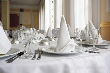 Place settings on an elegant, white dining table in a restaurant
