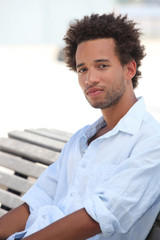 a young metis man sitting on wooden bench