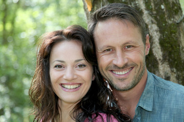 Fototapeta premium Portrait of smiling couple in forest
