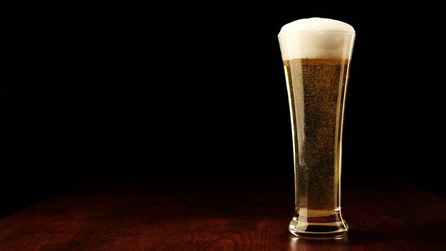 Beer into glass on a black and wooden table