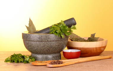 Mortar and pestle, bowls, parsley and pepper on yellow backgroun