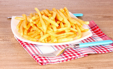 French fries on a plate and cutlery on a wooden background