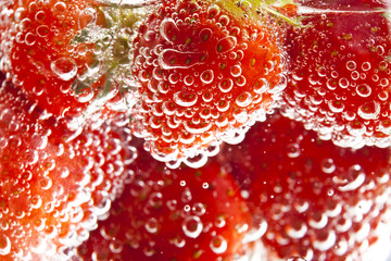 heap of strawberries in water with bubbles