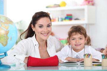 Little girl sat with teacher in class room