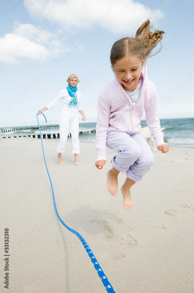 Wall mural family playing with skipping rope at the beach