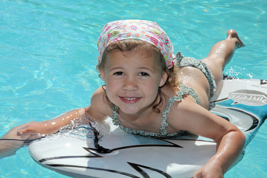 Baignade à la piscine sur une planche (fillette 4-5 ans)