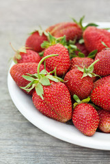 Fresh strawberries in bowl on old wooden table