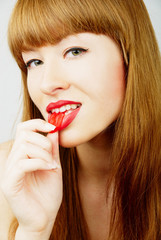 Red hair woman biting a red jelly candy
