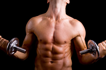 Fototapeta na wymiar Muscular young man lifting dumbbells on black background.