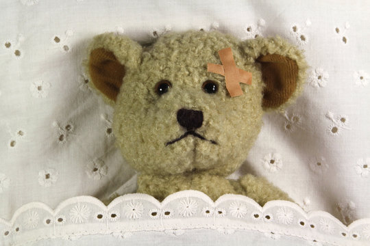 Teddy mit Pflaster im Bett