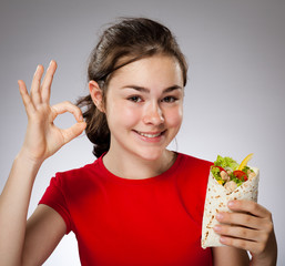 Girl eating big sandwich, showing Ok sign
