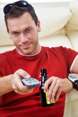 man with remote control and beer bottle