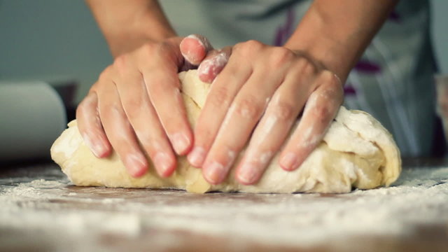 Female hands in flour kneading dough on table, time lapse