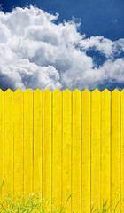 Fototapeta premium yellow picket fence and sky clouds