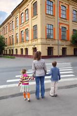 Obraz premium mother holds hand of little daughter and son and crossing