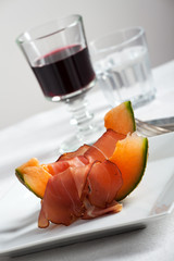 Schinkenscheiben und Melone mit Wein