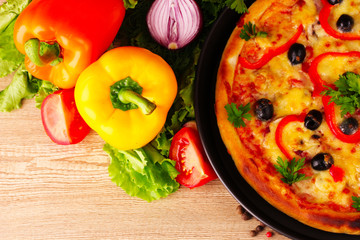 pizza and vegetables on wooden background