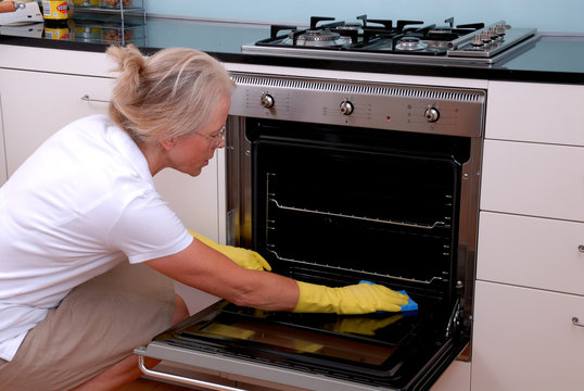 Frau putzt Backofen