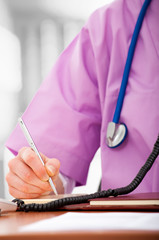 Closeup of a nurse writing something on a clipboard