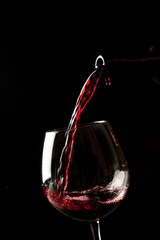 Red wine splash on a glass on black background. © Tommaso Lizzul