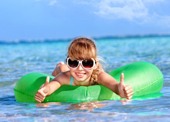 Child sitting on inflatable ring thumb up.