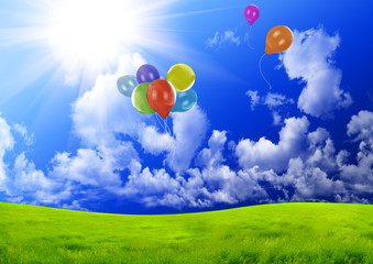 Fototapeta premium Color balloons in the dark blue sky over a green glade