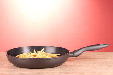 French fries in the pan on a red background