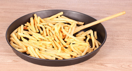 French fries and spoon in the pan on a wooden background